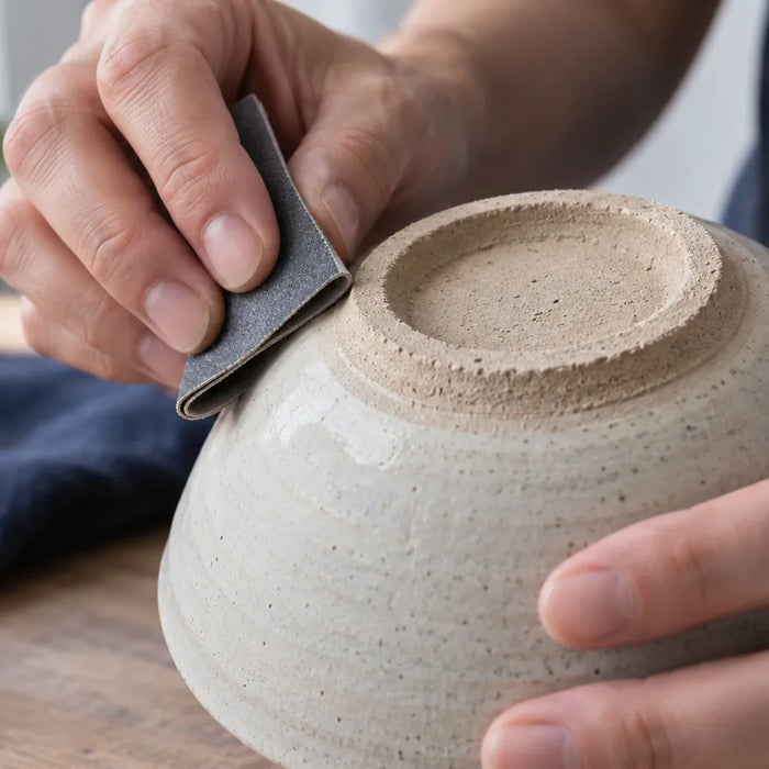 Hands inspecting a glossy hard-surface sample under angled light without sanding.